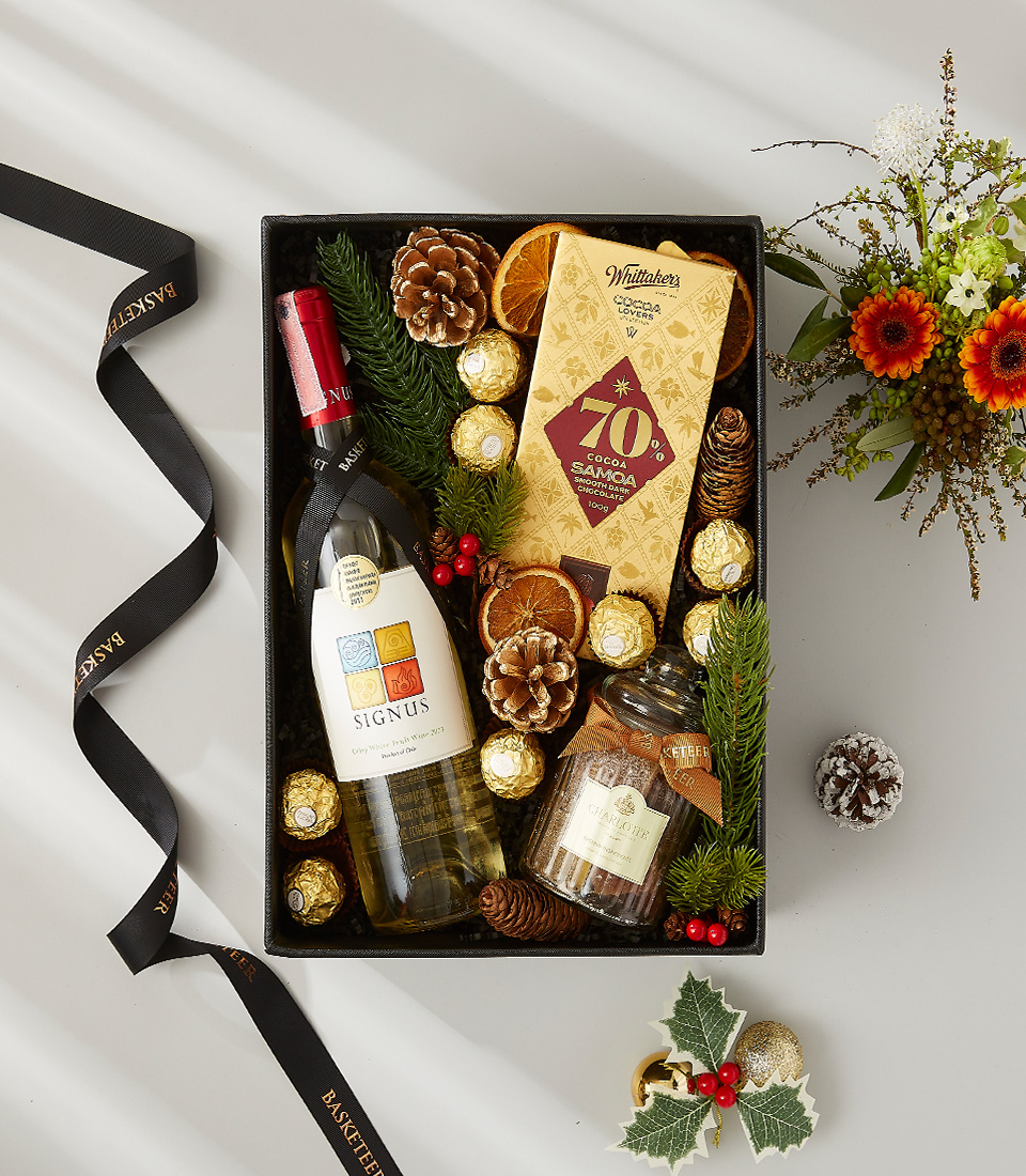 A luxurious holiday gift box filled with a bottle of white wine, a selection of fine chocolates, and fragrant candles.