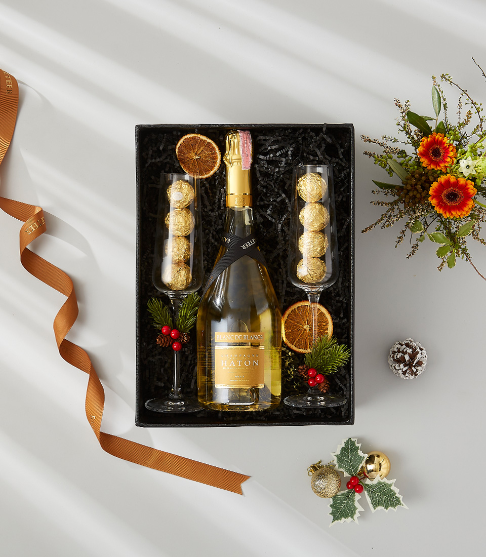 Festive gift box containing a bottle of Moët & Chandon champagne, gourmet chocolate, and two champagne flutes.