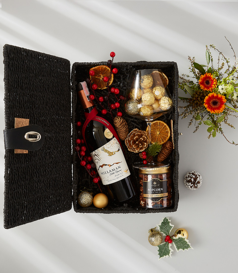 A luxurious holiday gift basket filled with a bottle of Prosecco, a selection of gourmet snacks, and festive decorations.