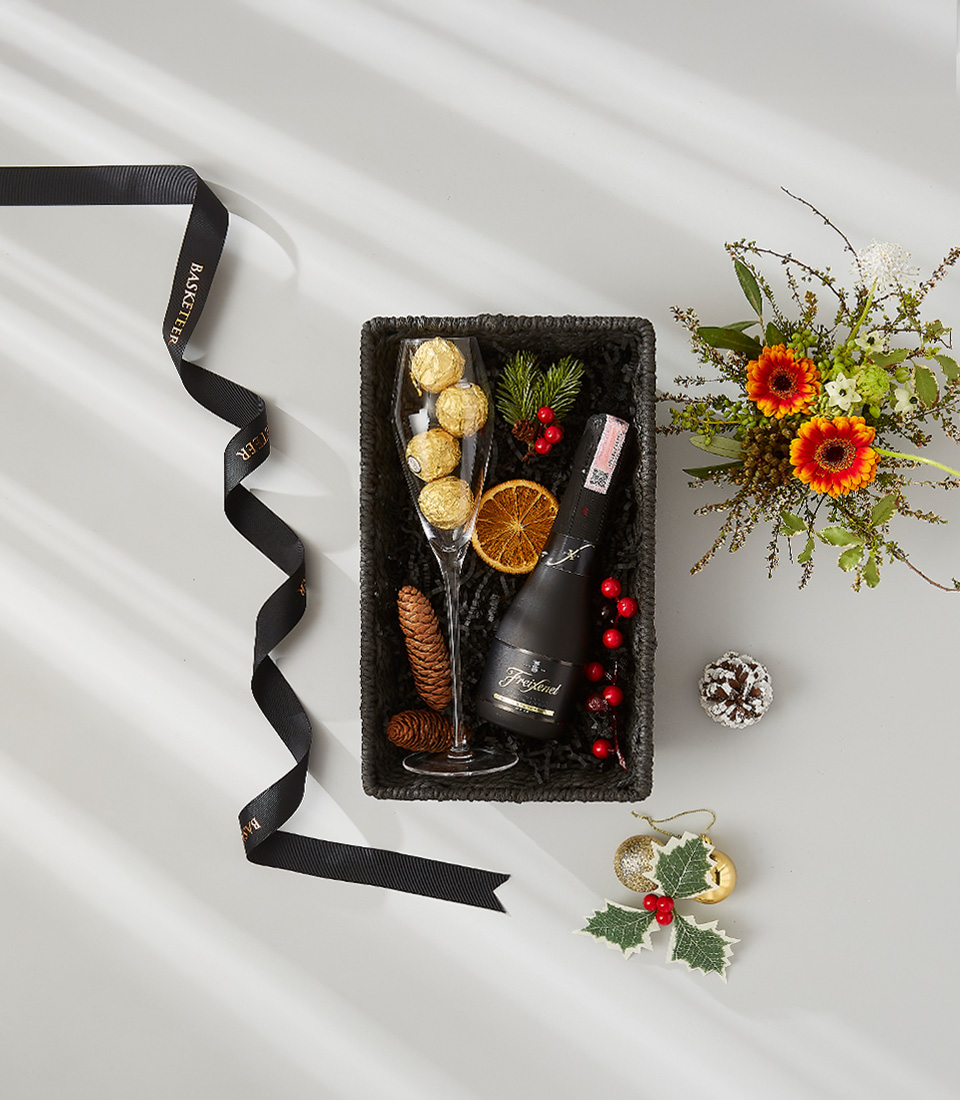 A luxurious holiday gift basket filled with a bottle of Freixenet Prosecco, a selection of gourmet snacks, and festive decorations.
