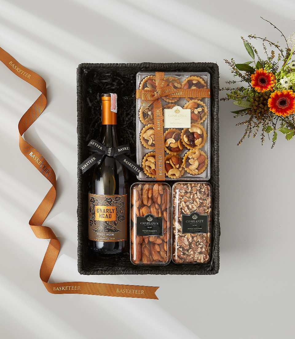 A luxurious gift hamper filled with a bottle of wine, gourmet snacks, and festive decorations.