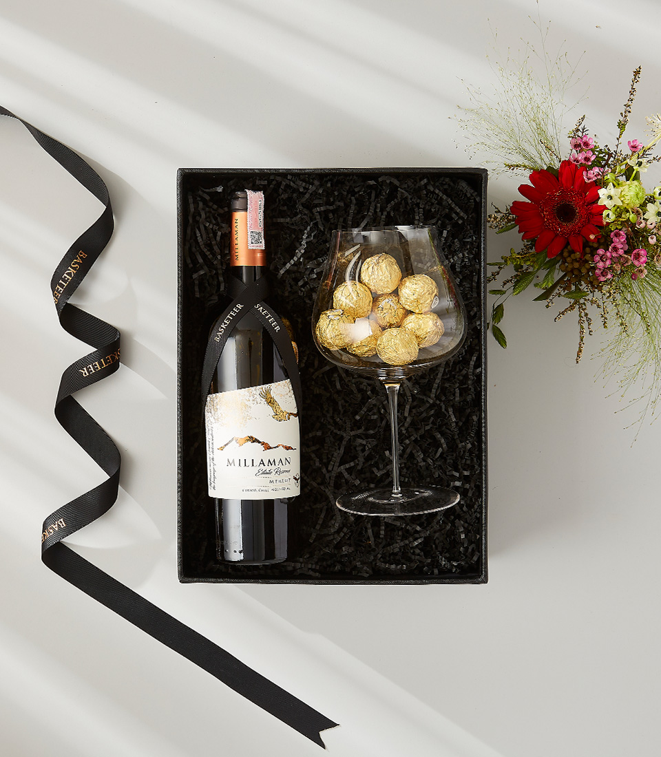 A luxurious gift box filled with a bottle of wine, a glass of chocolates