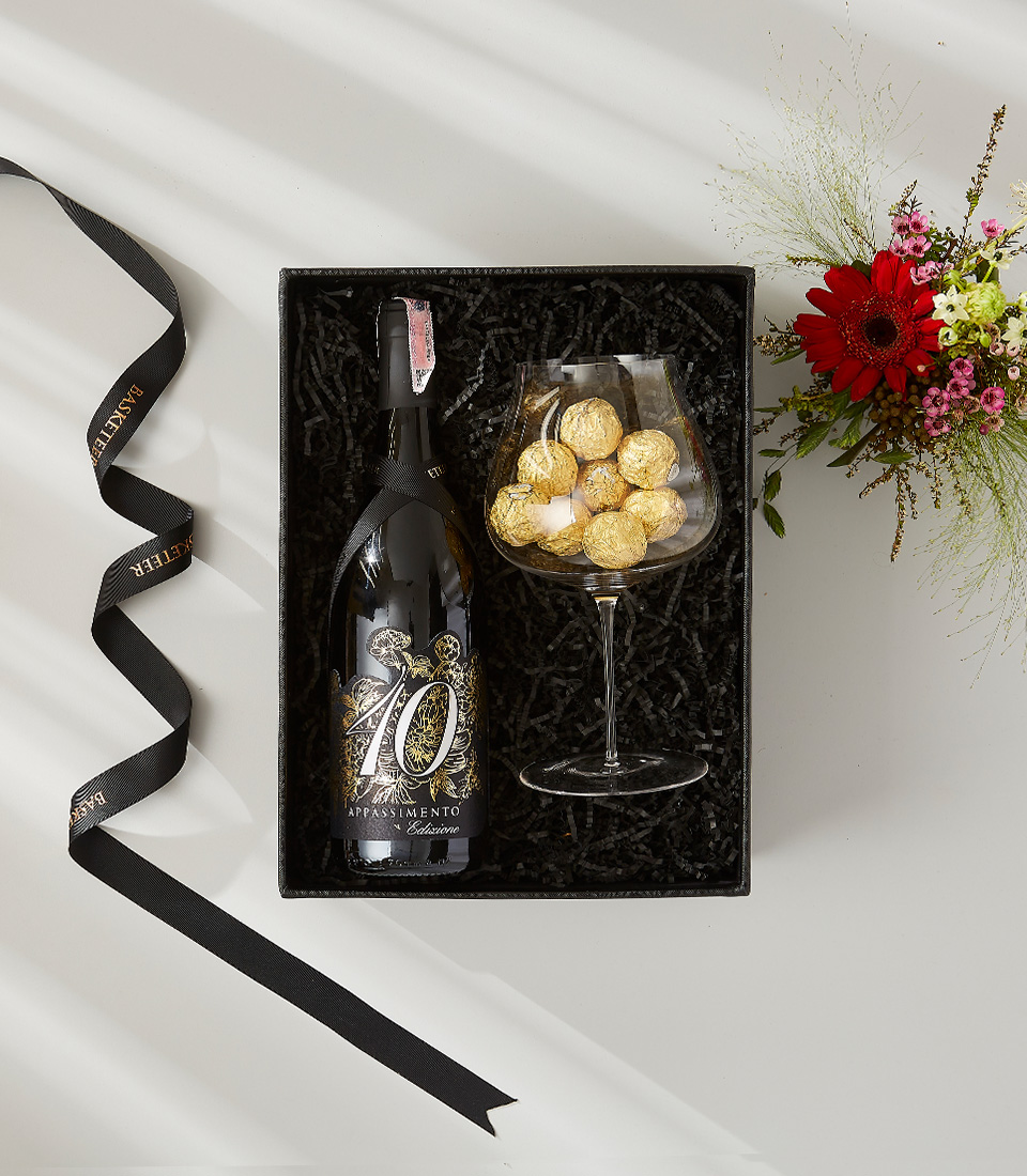 A luxurious gift box filled with a bottle of wine, a glass of chocolates