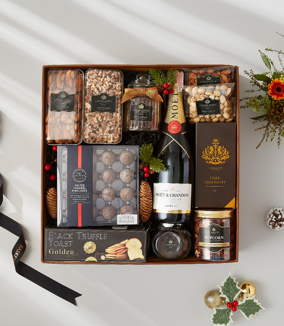 a festive gift box filled with a bottle of Champagne , decadent snacks, and holiday-scented candles.
