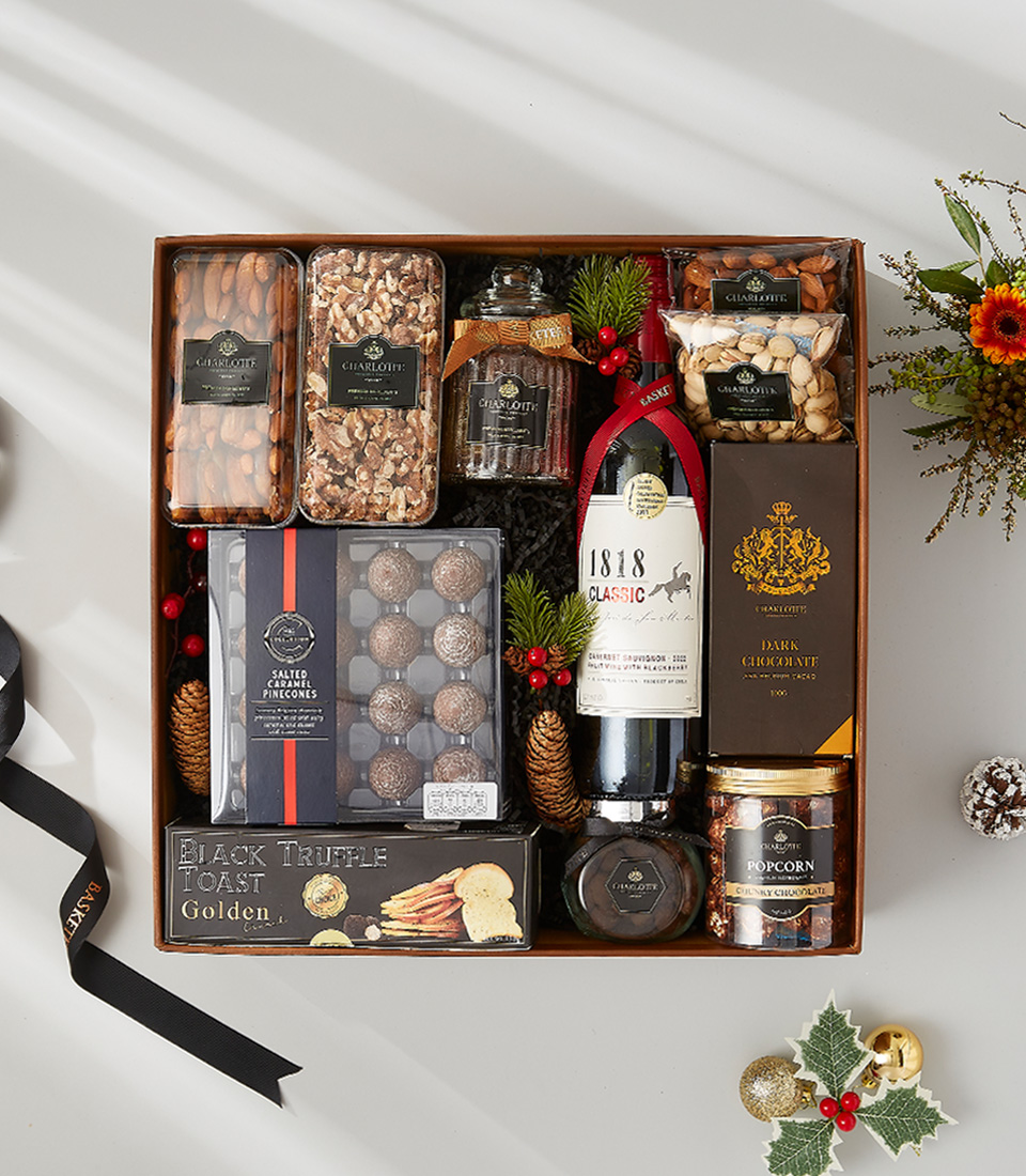 A luxurious and elegant gift basket filled with a bottle of wine, gourmet snacks, and holiday decorations.