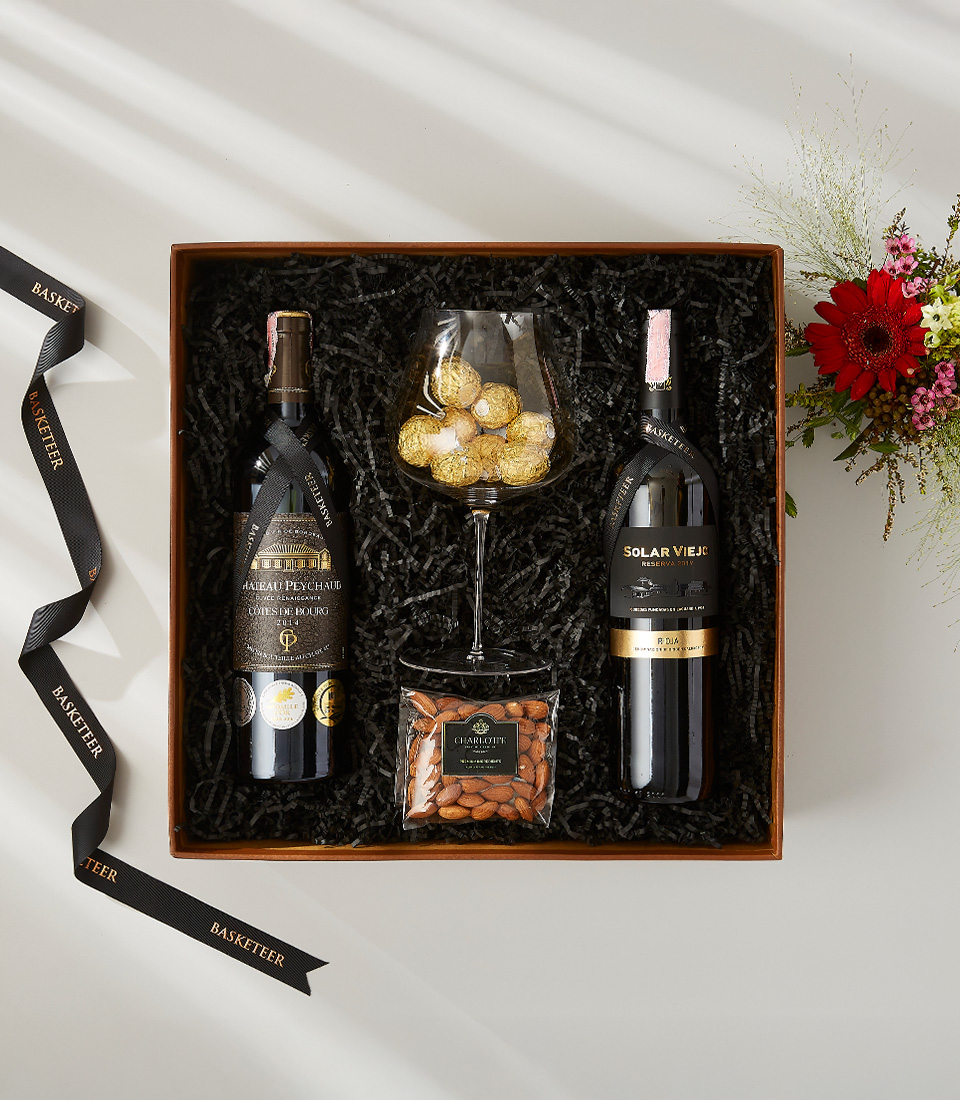 Château Peychaud and Solar Viejo red wine gift set with almonds, chocolate truffles, and a wine glass.