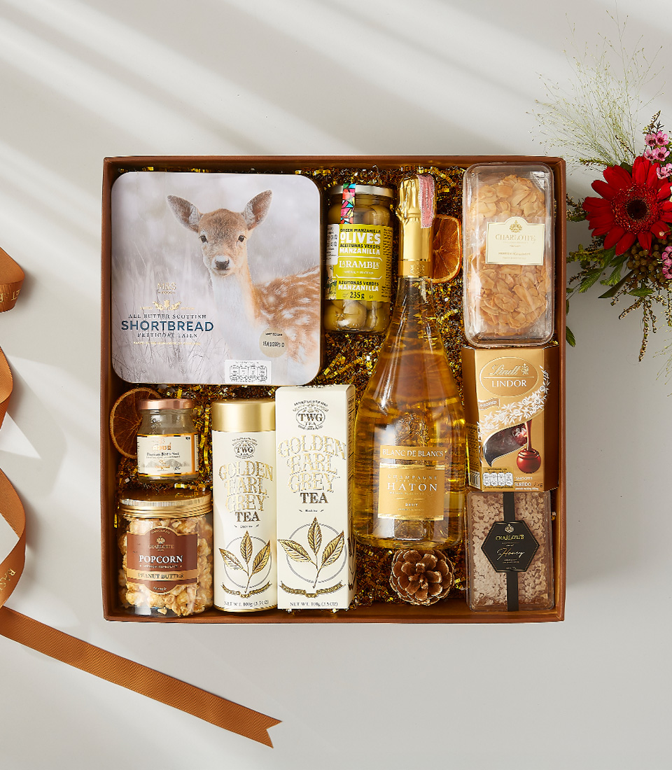 Luxurious gift box with champagne, gourmet tea, shortbread, popcorn, olives, and assorted treats, perfect for special celebrations.
