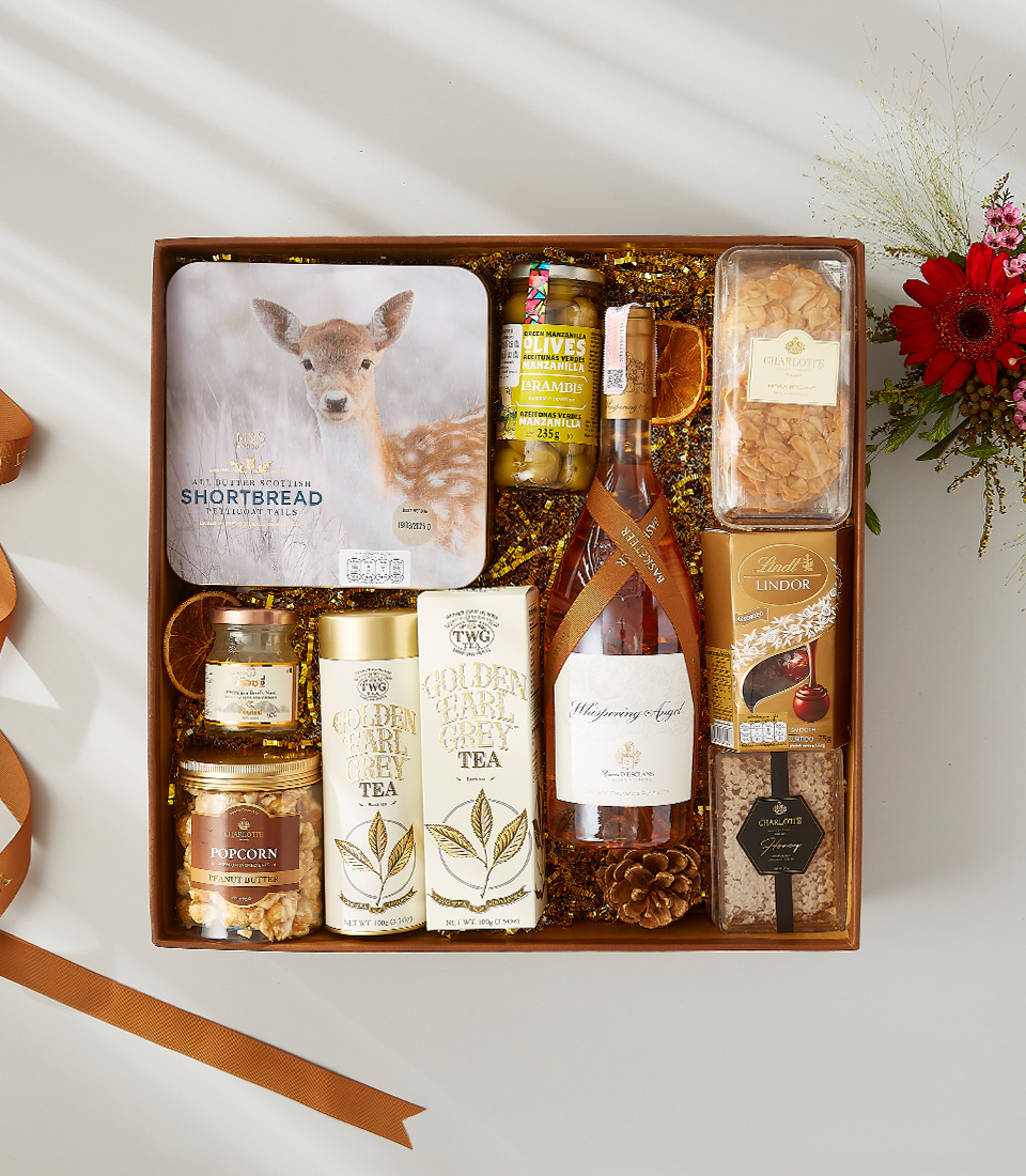 Luxury gift hamper with rosé wine, gourmet tea, Scottish shortbread, olives, popcorn, chocolates, and assorted treats.
