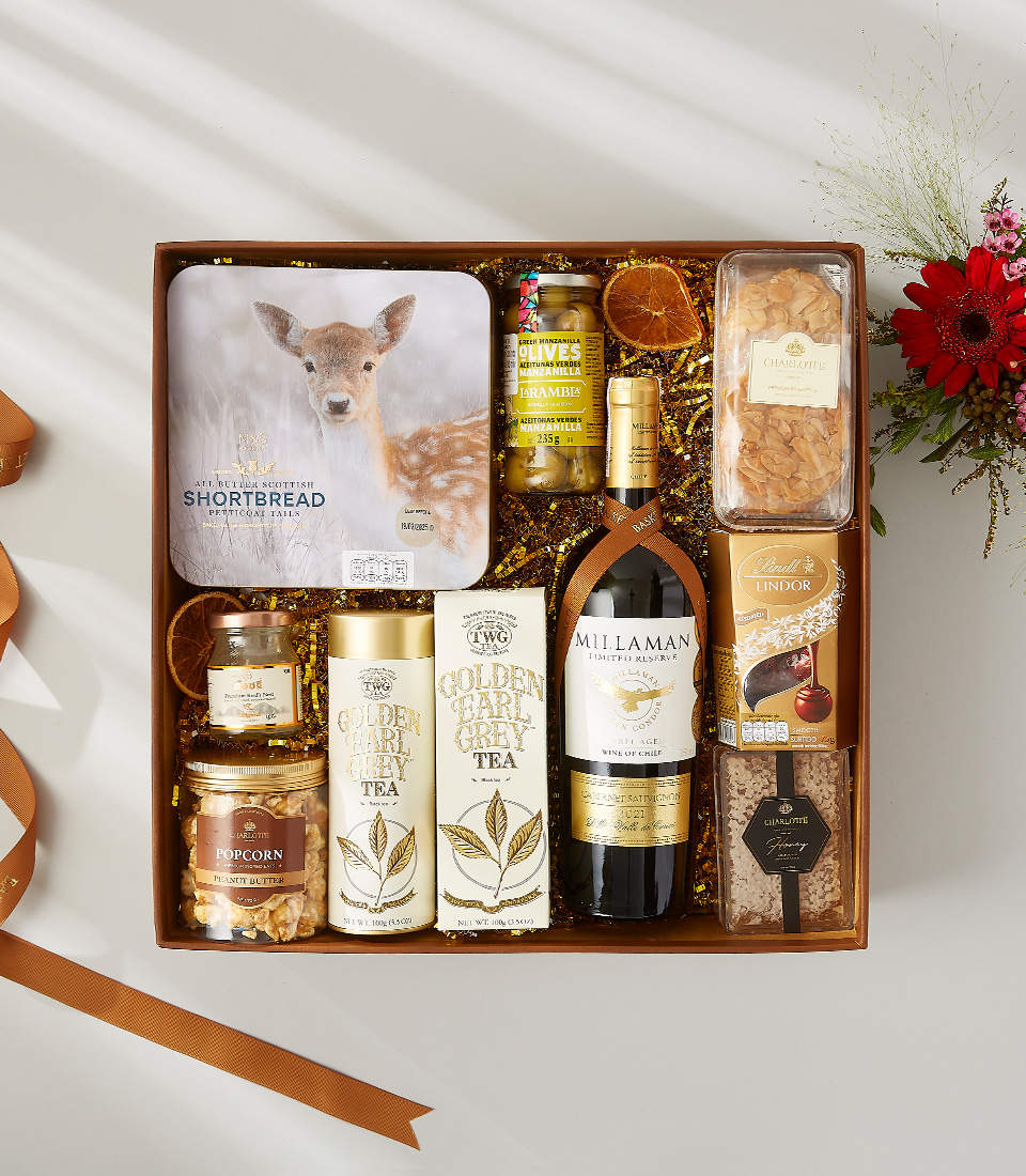 Luxury gift hamper with red wine, premium tea, Scottish shortbread, olives, popcorn, chocolates, and assorted gourmet treats.