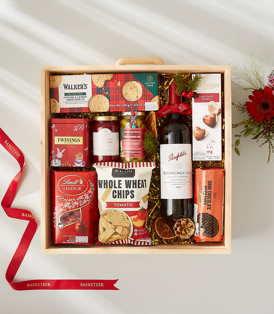 A luxurious Christmas gift basket filled with a bottle of wine, assorted cookies, nuts, chocolates, and other festive goodies.