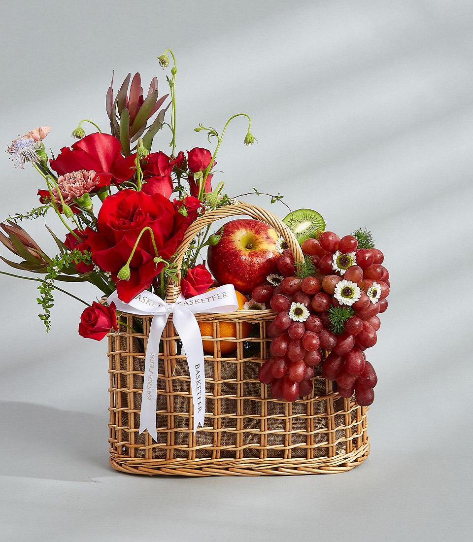 Floral fruit basket with red roses, fresh apples, grapes, and a white decorative ribbon. Title: Floral Fruit Basket with Red Roses - Perfect Gift for Any Occasion