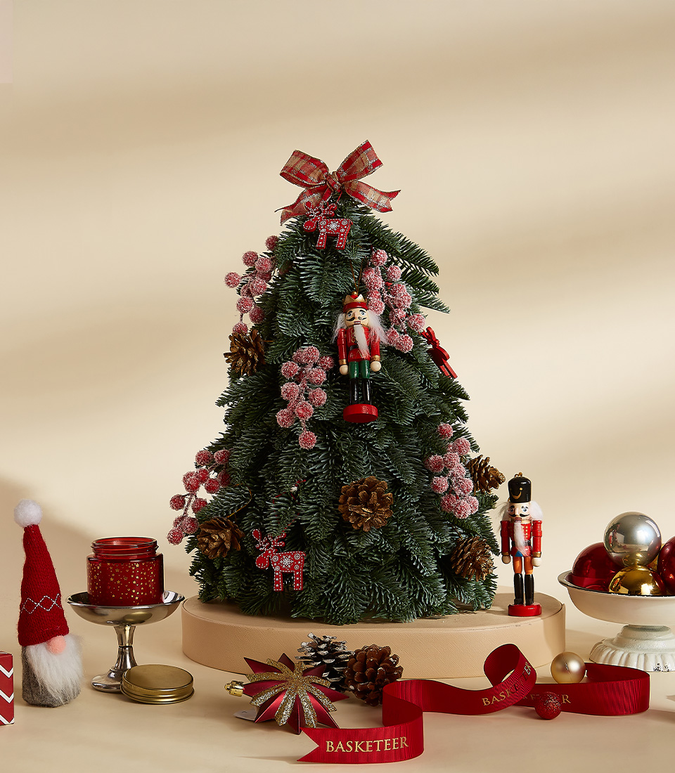 Mini Christmas tree with nutcracker decorations, red ornaments, pinecones, and plaid ribbon topper.