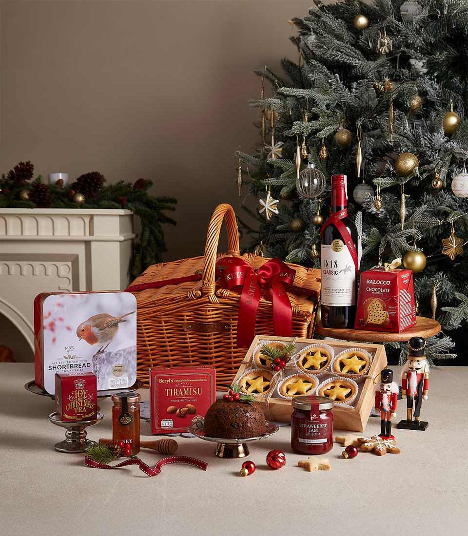 Classic Christmas hamper with shortbread, tiramisu, pudding, and strawberry jam, displayed near a Christmas tree with festive decorations.