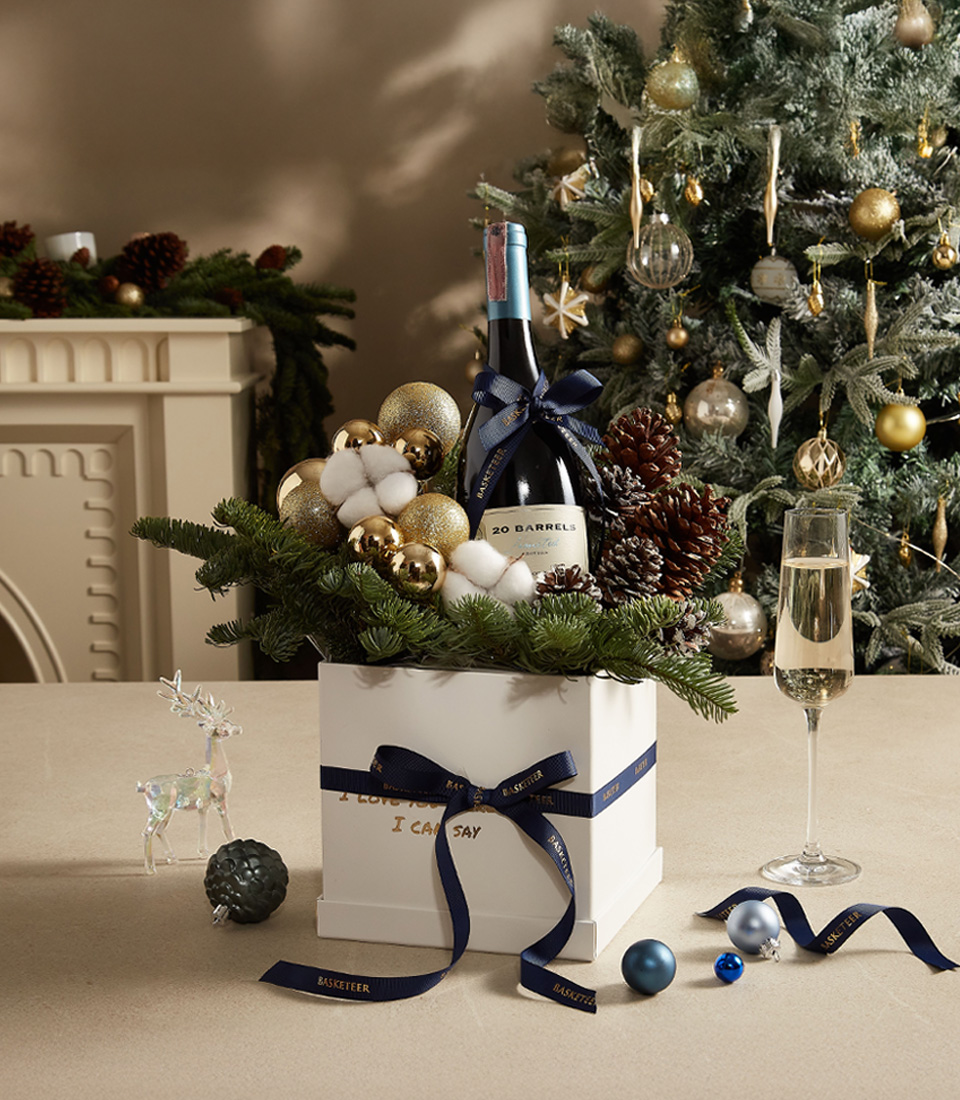 White Christmas gift box with pine greenery, ornaments, and festive decorations for a joyful holiday presentation.