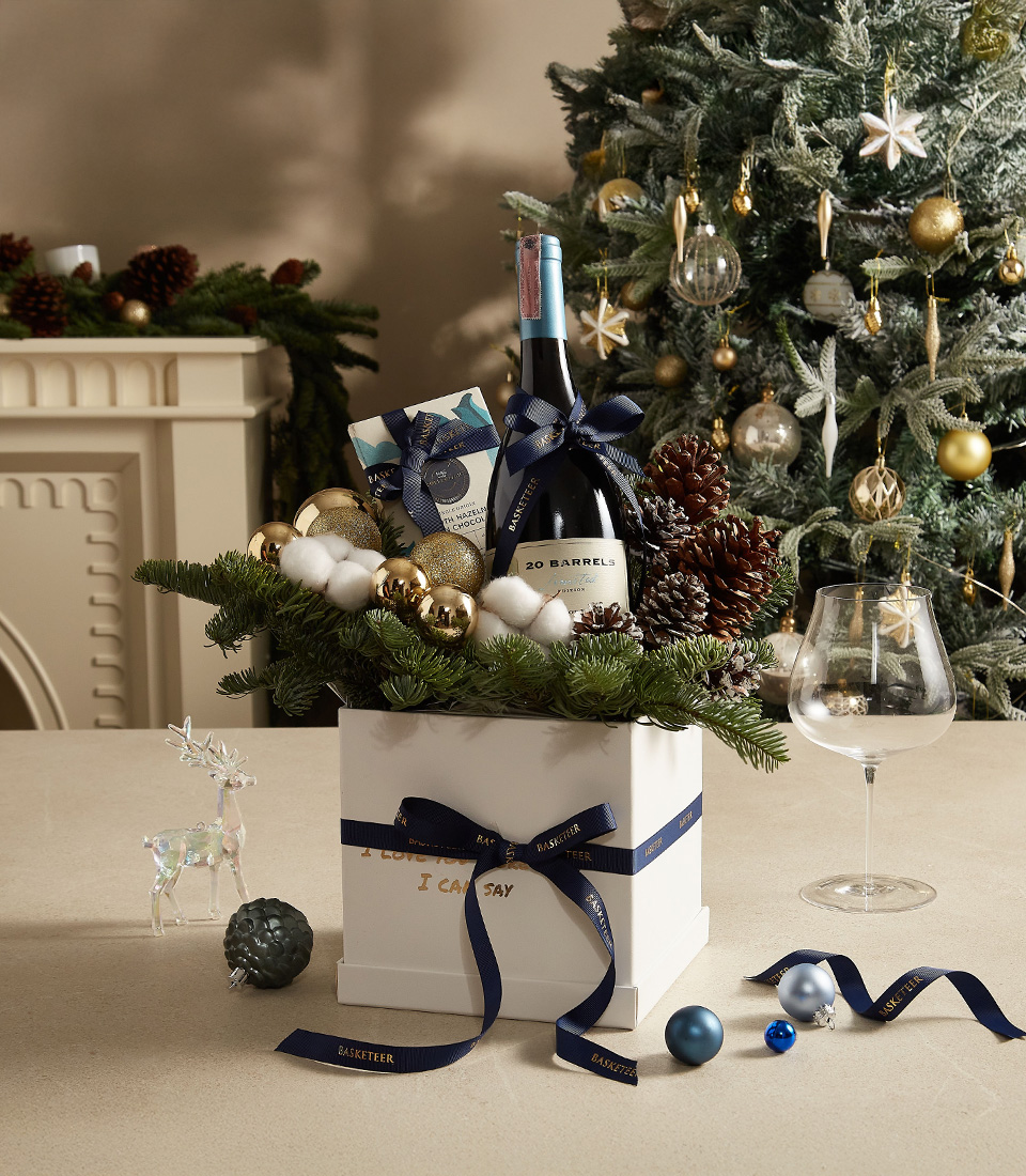 Christmas gift box with pine greenery, ornaments, and premium holiday treats, ideal for festive gifting.