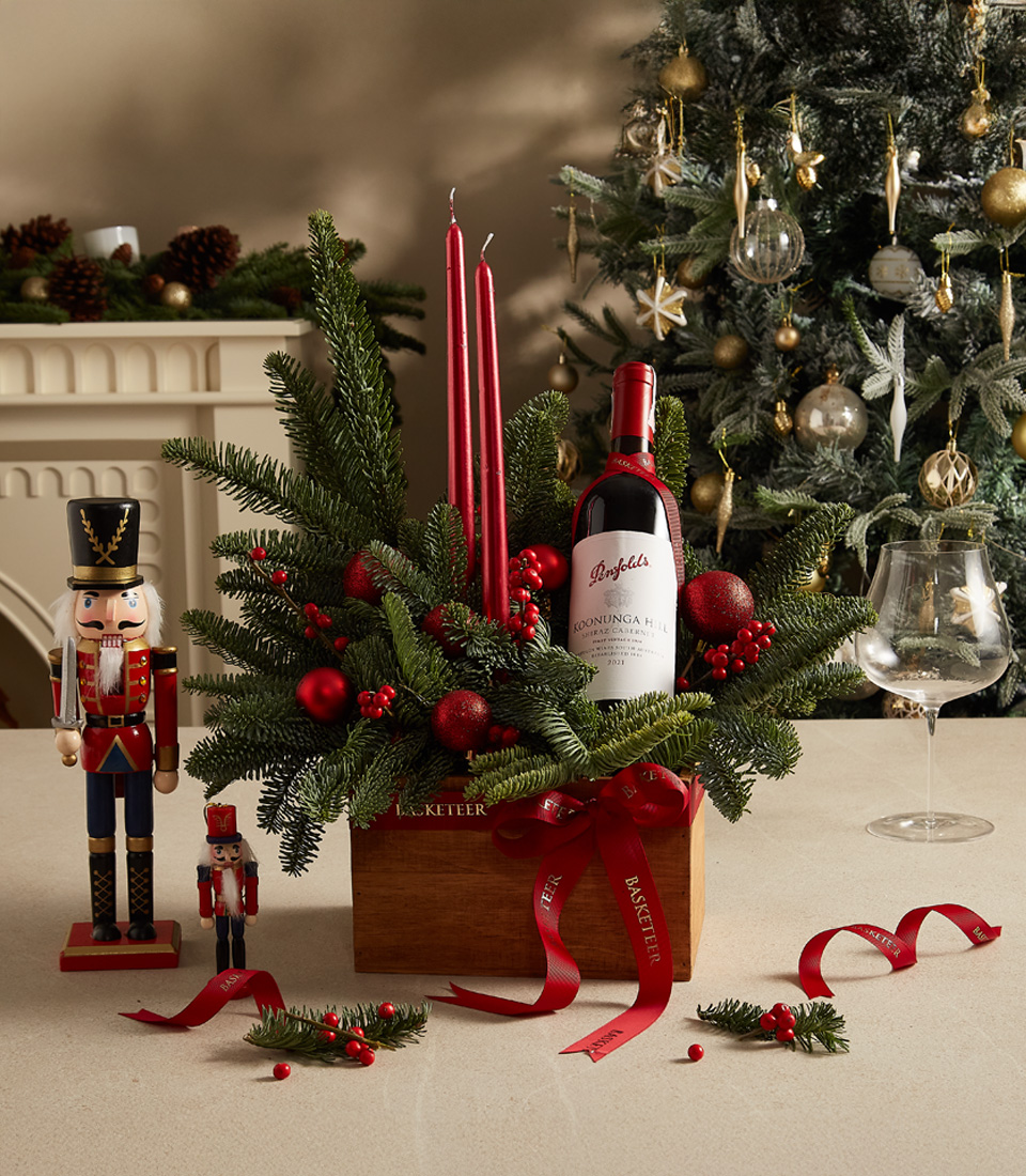 Holiday gift box with red candles, lush greenery, and decorative festive accents for a warm celebration.