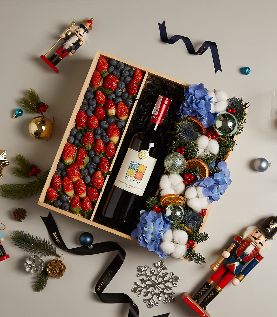 Gift box with strawberries, blueberries, and elegant floral decorations for festive celebrations.