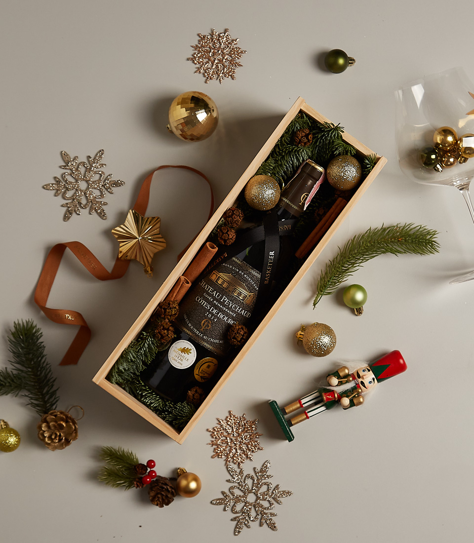 Festive gift box featuring a premium red beverage, holiday ornaments, and decorations.