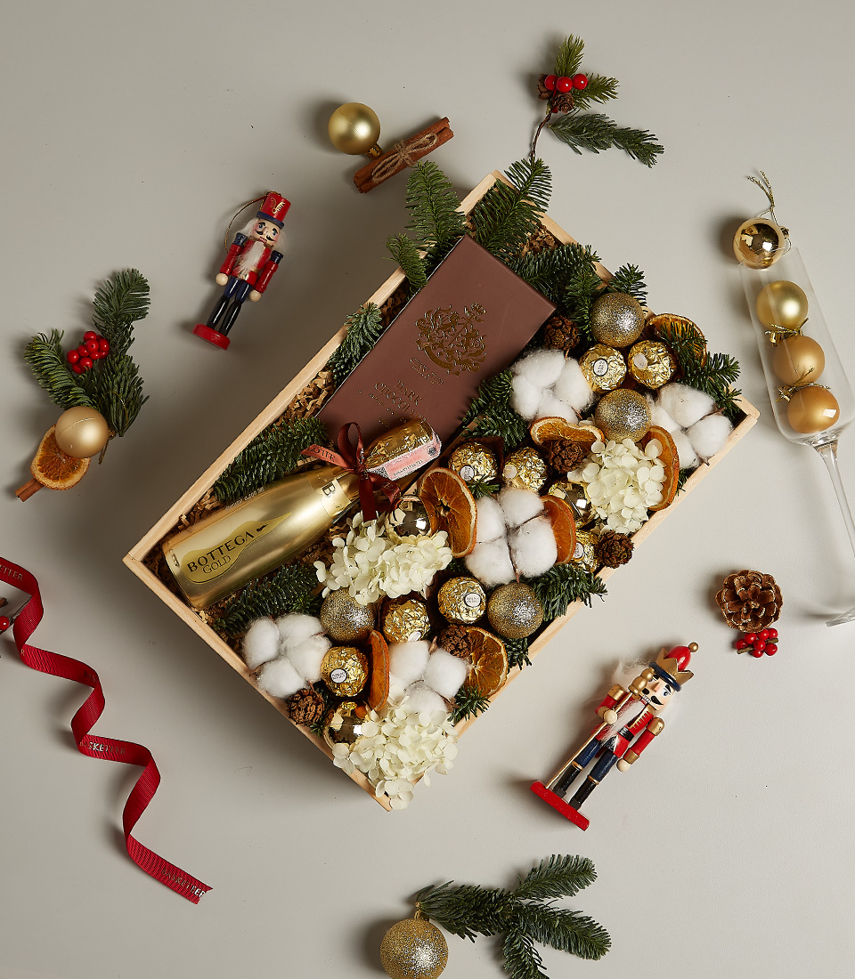 Luxurious golden festive gift box with premium chocolates, treats, and elegant holiday decorations.