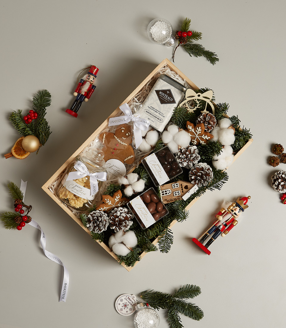 Winter-themed gourmet gift box with cookies, chocolates, hot cocoa, and festive holiday decorations.