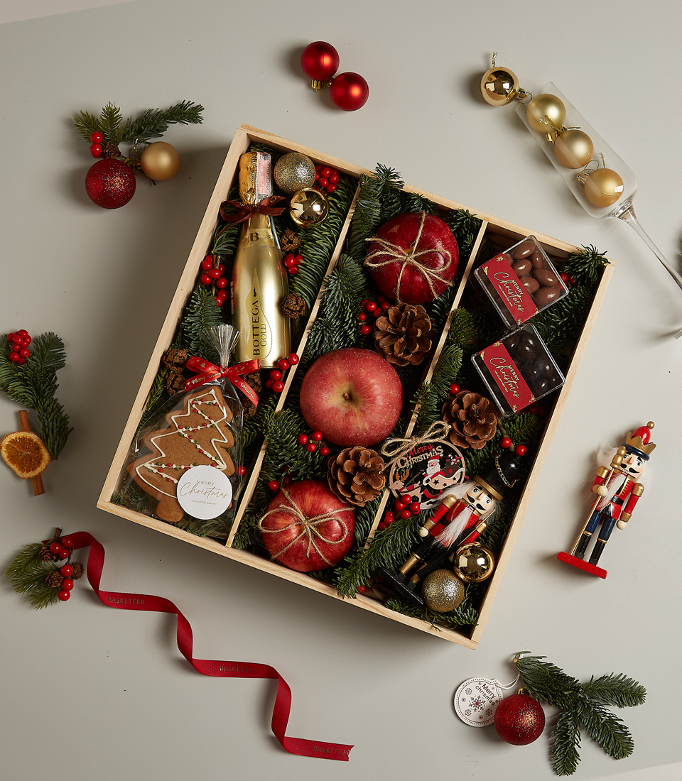Christmas gift box featuring Bottega Gold Prosecco, apples, chocolates, gingerbread cookie, nutcracker, and festive holiday decor.