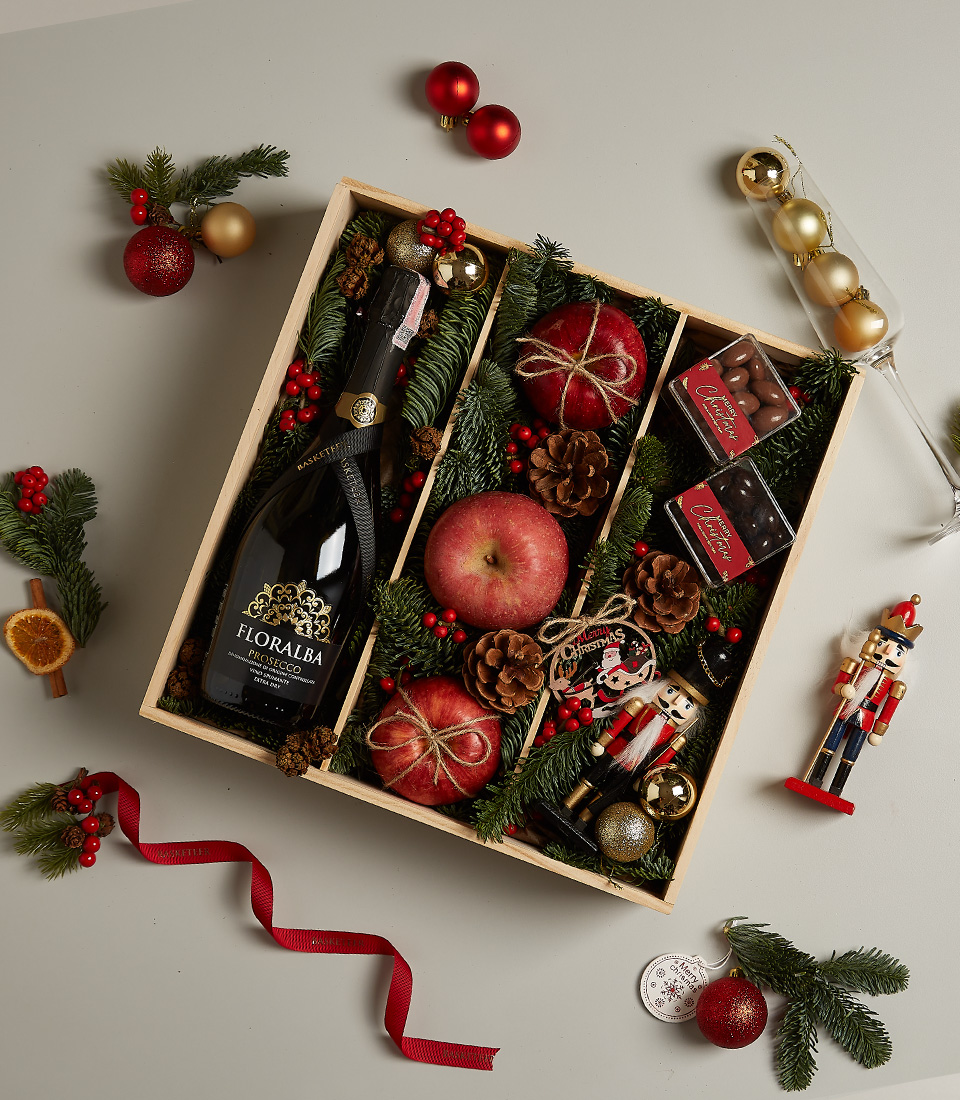 Luxurious Christmas gift box with Floralba Prosecco, apples, chocolates, pinecones, and festive decorations.