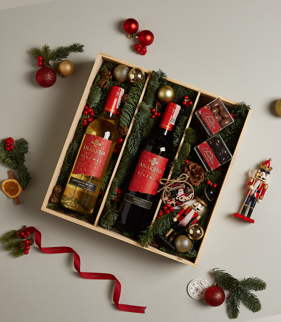 Holiday gift box with Anakena red and white wines, chocolates, nutcracker, and festive decorations.