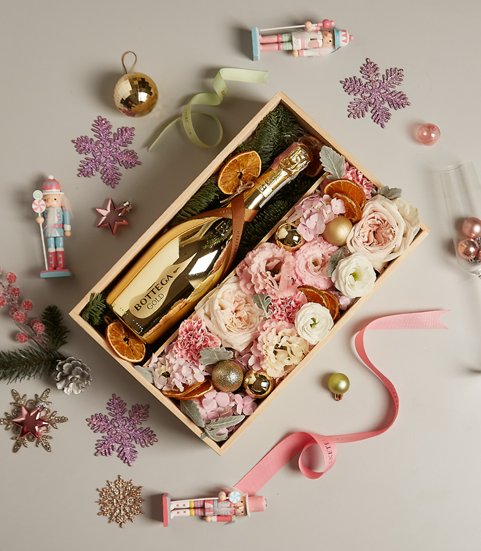 Blush and gold-themed gift hamper featuring Bottega Gold Prosecco, pastel floral arrangements, and festive decorations.