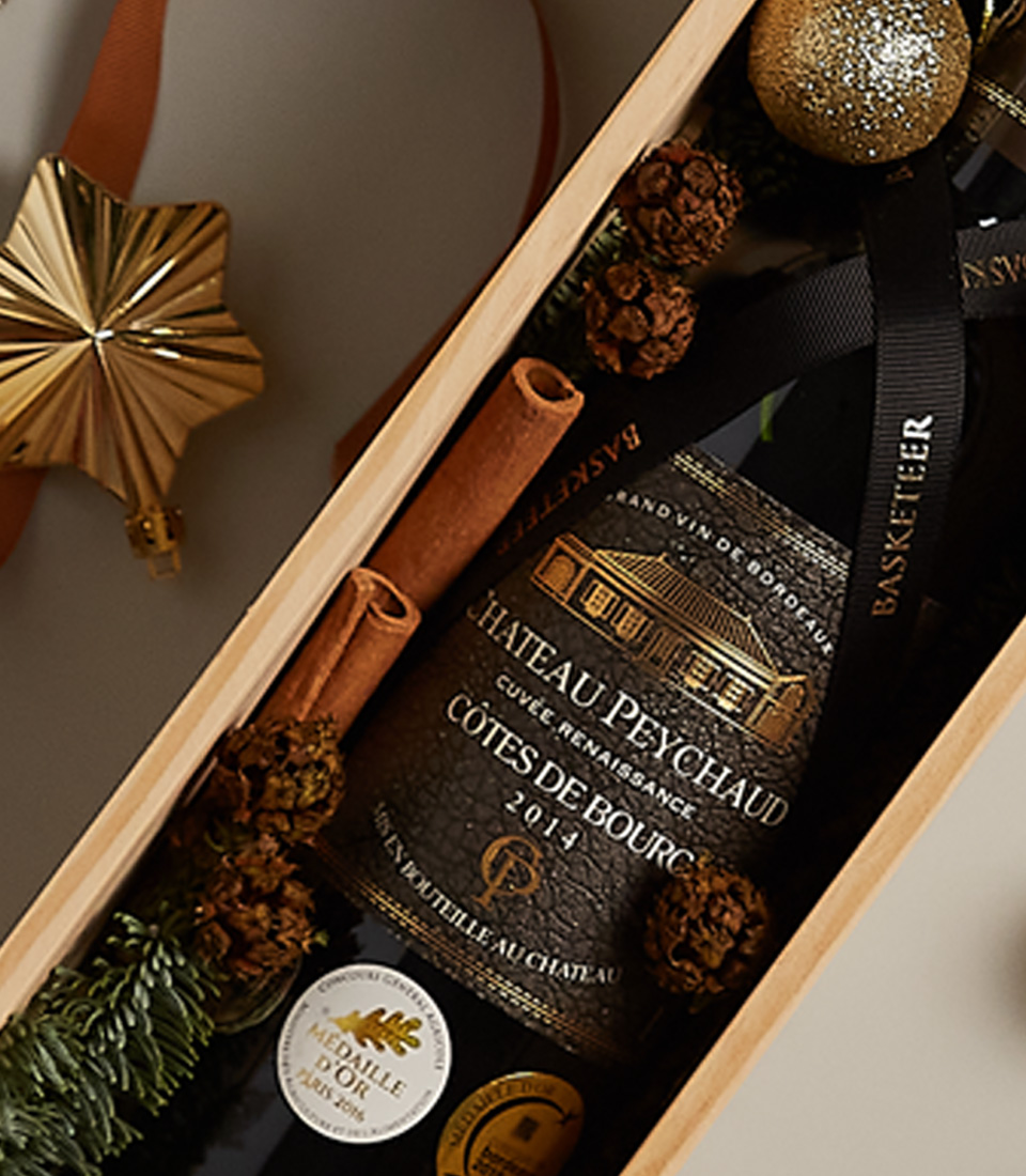 Festive gift box featuring a premium red beverage, holiday ornaments, and decorations.