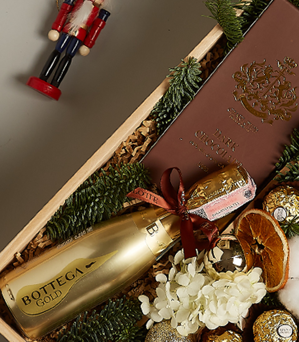 Luxurious golden festive gift box with premium chocolates, treats, and elegant holiday decorations.