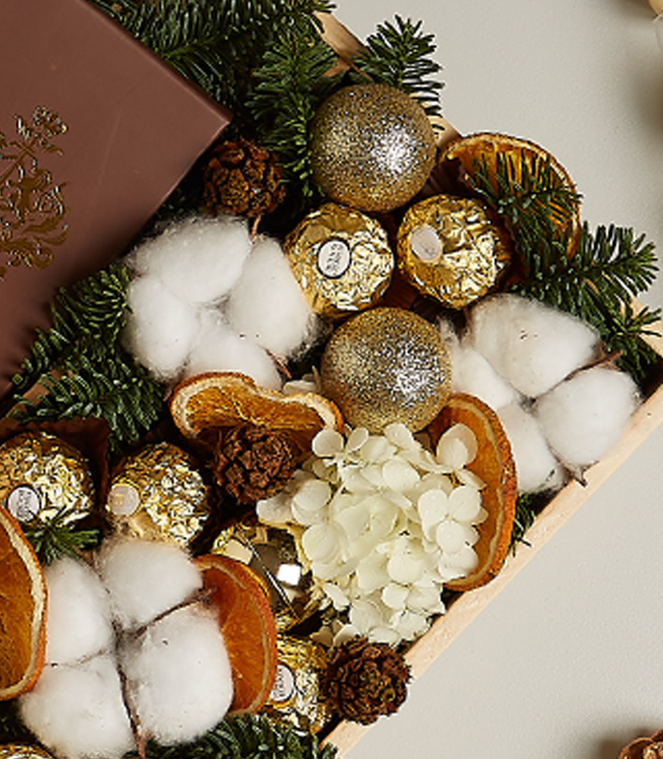 Luxurious golden festive gift box with premium chocolates, treats, and elegant holiday decorations.