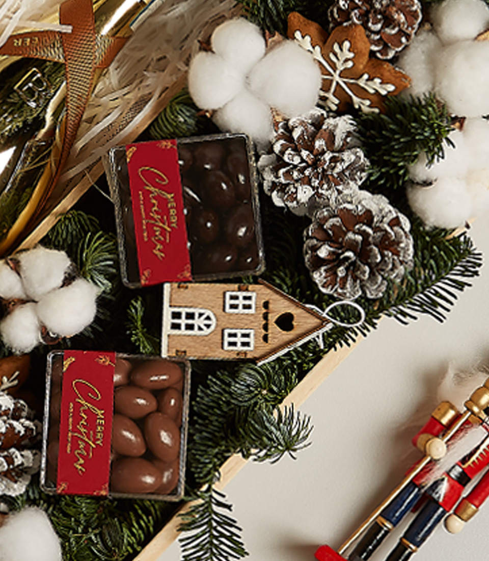 Christmas gift box with Bottega Gold Prosecco, chocolates, gingerbread ornament, pinecones, and festive holiday decor.