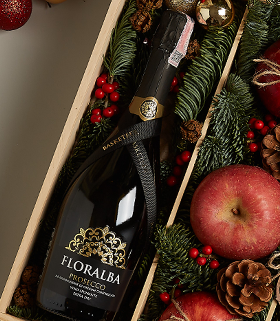 Luxurious Christmas gift box with Floralba Prosecco, apples, chocolates, pinecones, and festive decorations.