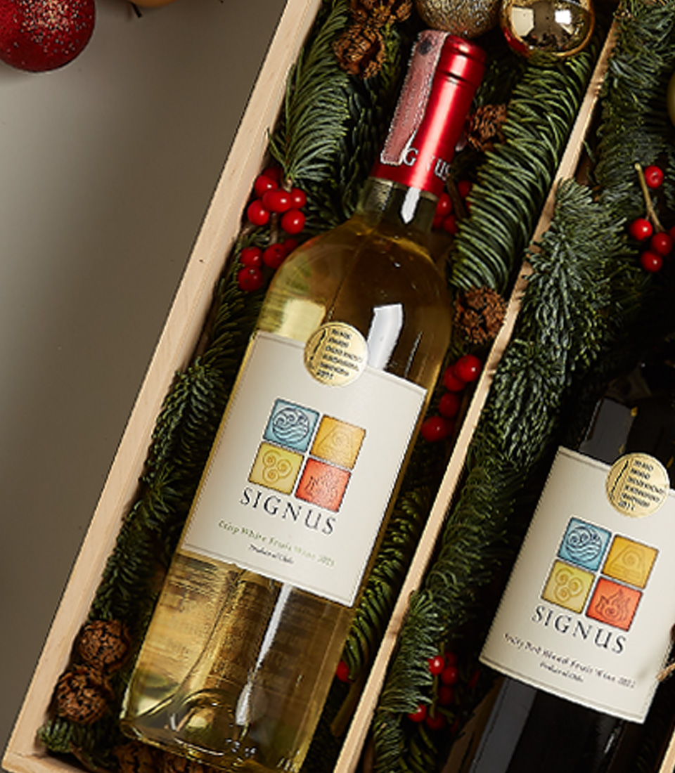 Christmas gift box with red and white Signus wines, chocolates, nutcracker, and holiday decorations.