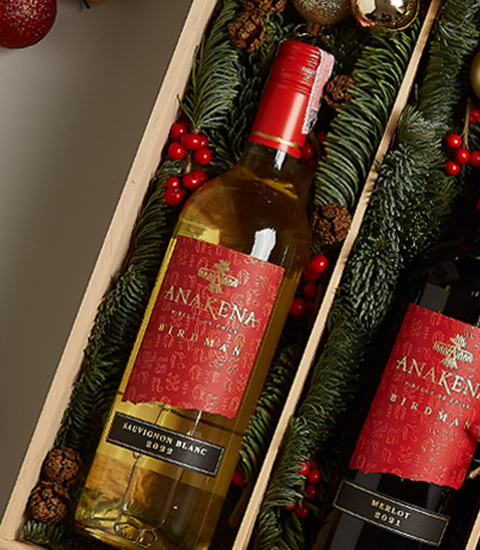 Holiday gift box with Anakena red and white wines, chocolates, nutcracker, and festive decorations.