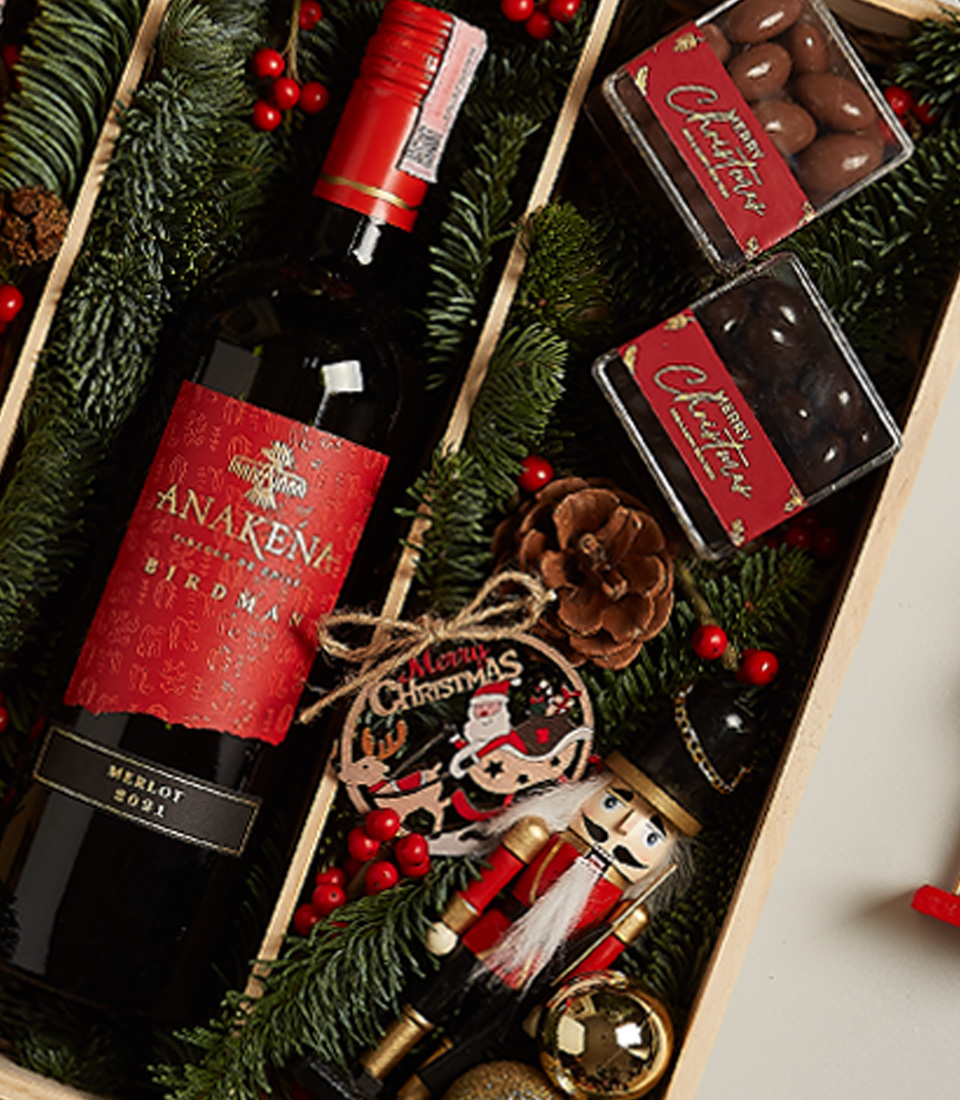 Holiday gift box with Anakena red and white wines, chocolates, nutcracker, and festive decorations.