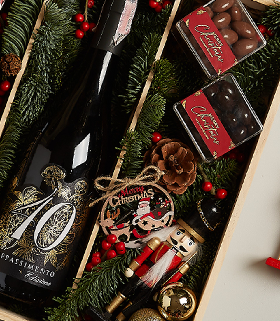 Luxurious gift box with Château Peychaud red wine, Pasqua 10 Anniversario wine, holiday chocolates, nutcracker, and festive decorations.
