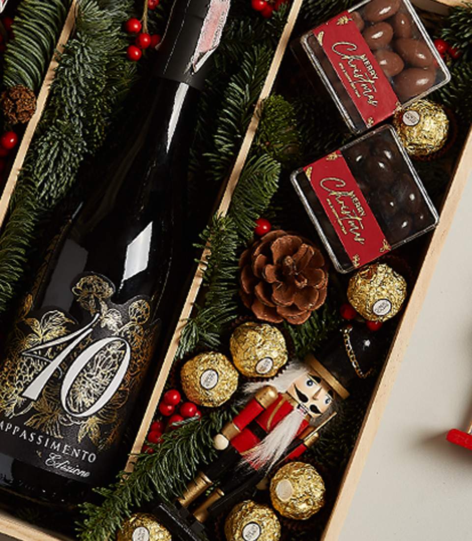 Premium holiday gift box featuring Château Peychaud red wine, Pasqua 10 Anniversario wine, Ferrero Rocher chocolates, nutcracker, and Christmas-themed decor.