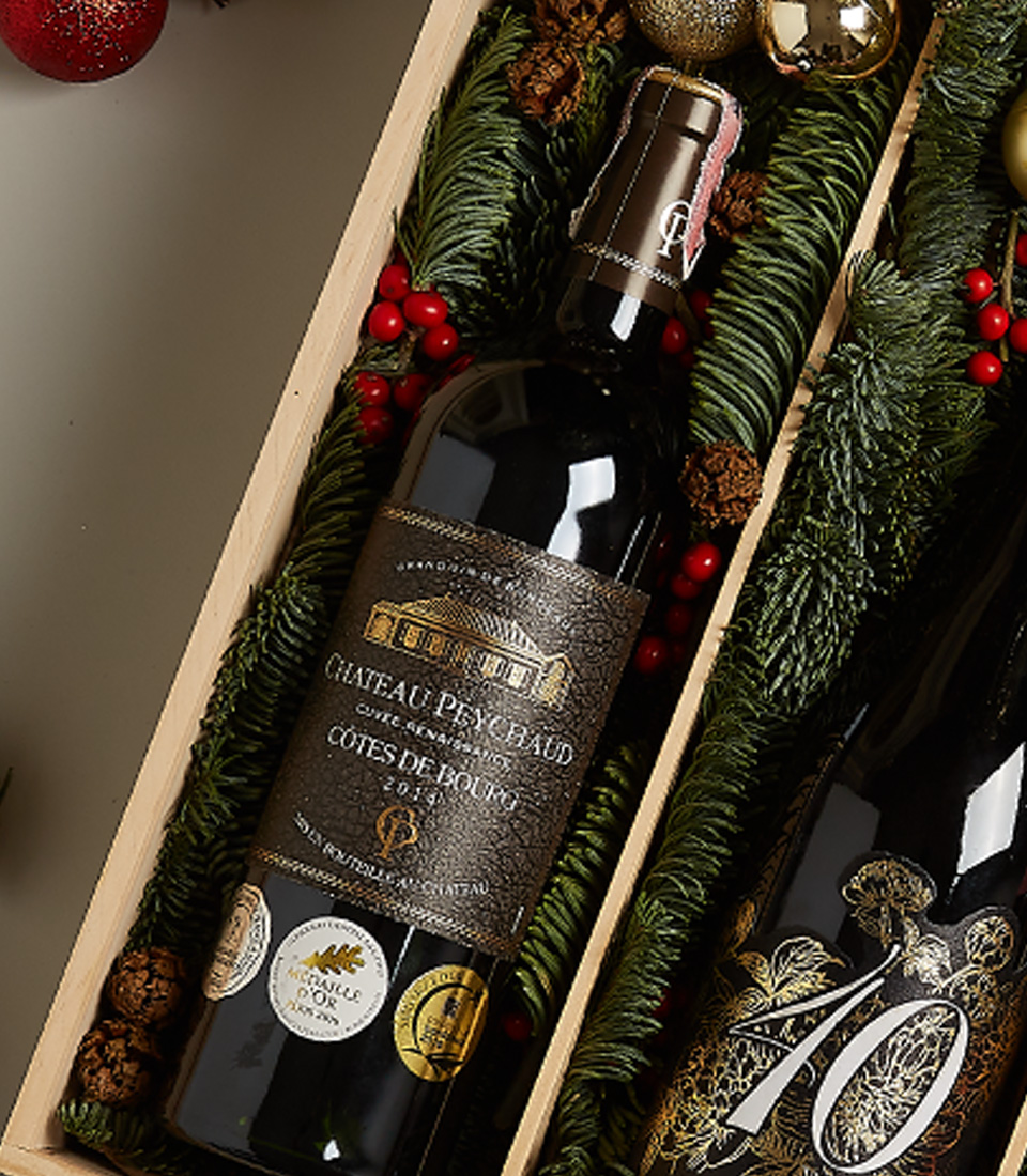 Holiday gift hamper featuring Château Peychaud red wine, Pasqua 10 Anniversario wine, fresh strawberries, cherries, and Christmas-themed decorations.