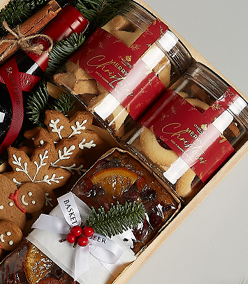 Gift box with Penfolds Koonunga Hill Shiraz Cabernet, gingerbread cookies, fruitcake, biscuits, chocolates, and festive decorations.