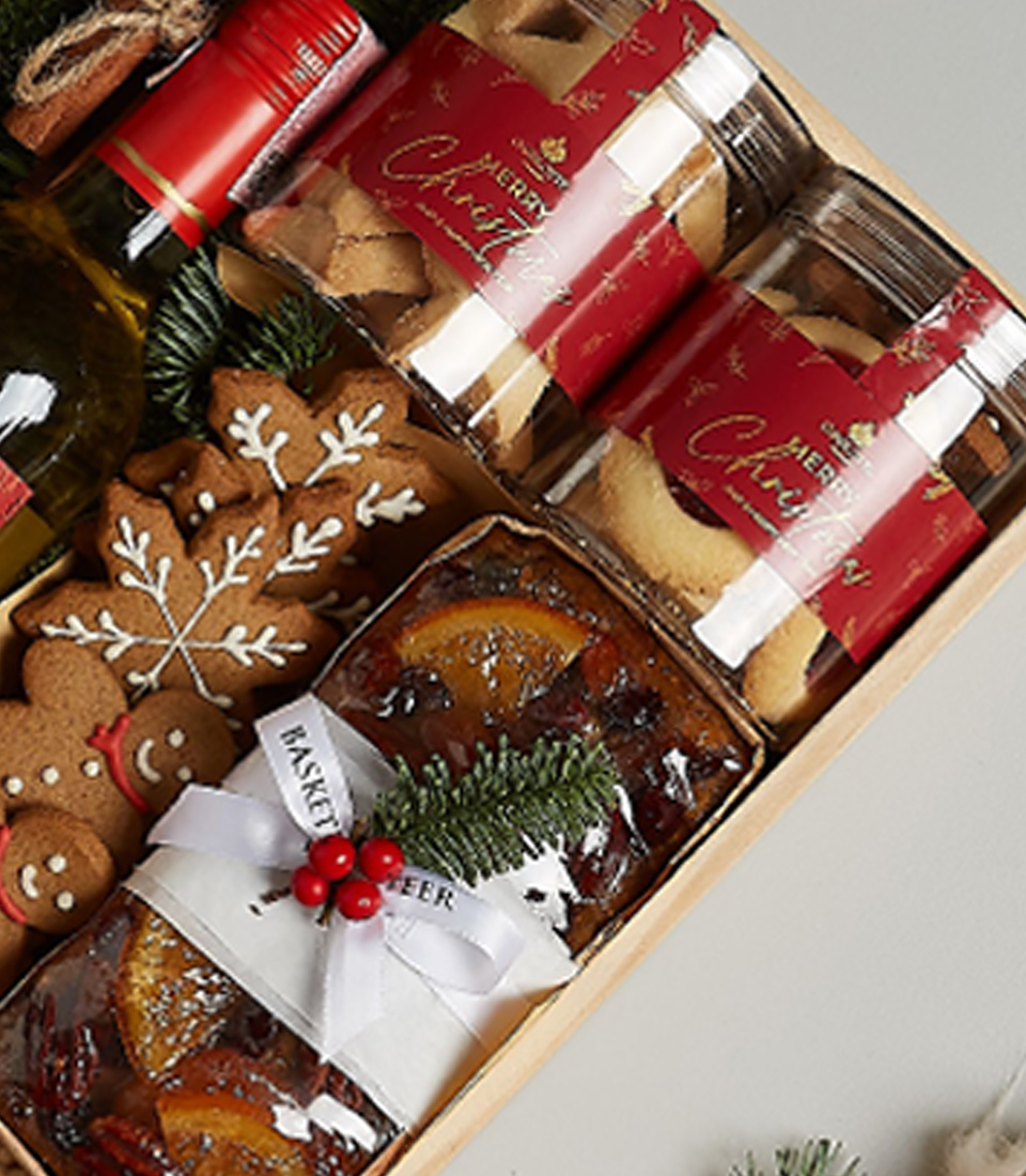 Holiday gift box featuring Anakena Sauvignon Blanc, gingerbread cookies, biscuits, chocolates, fruitcake, and festive decorations.