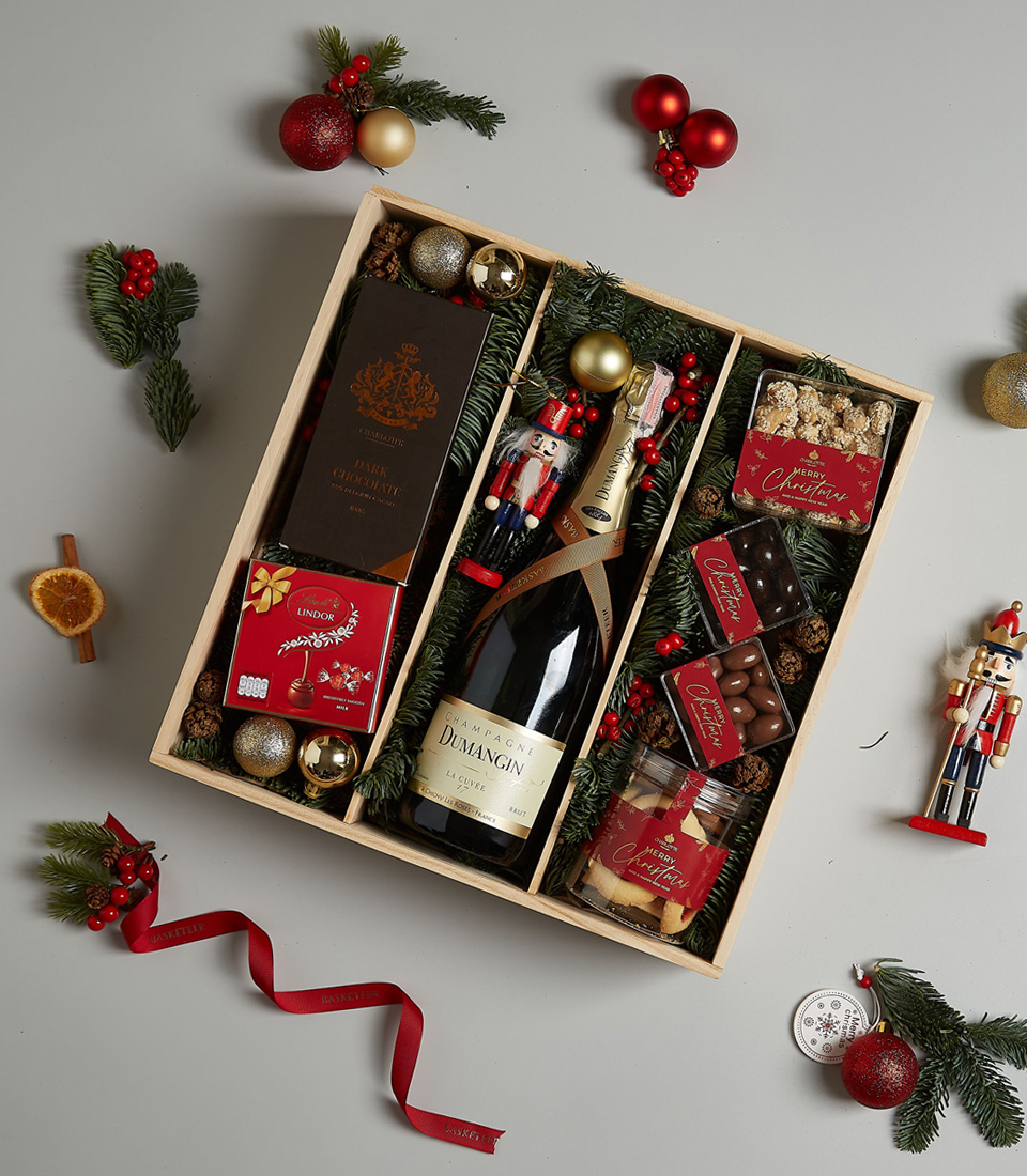 Luxurious holiday gift box featuring Champagne Dumangin, dark chocolate, Lindt pralines, festive cookies, and holiday decorations.