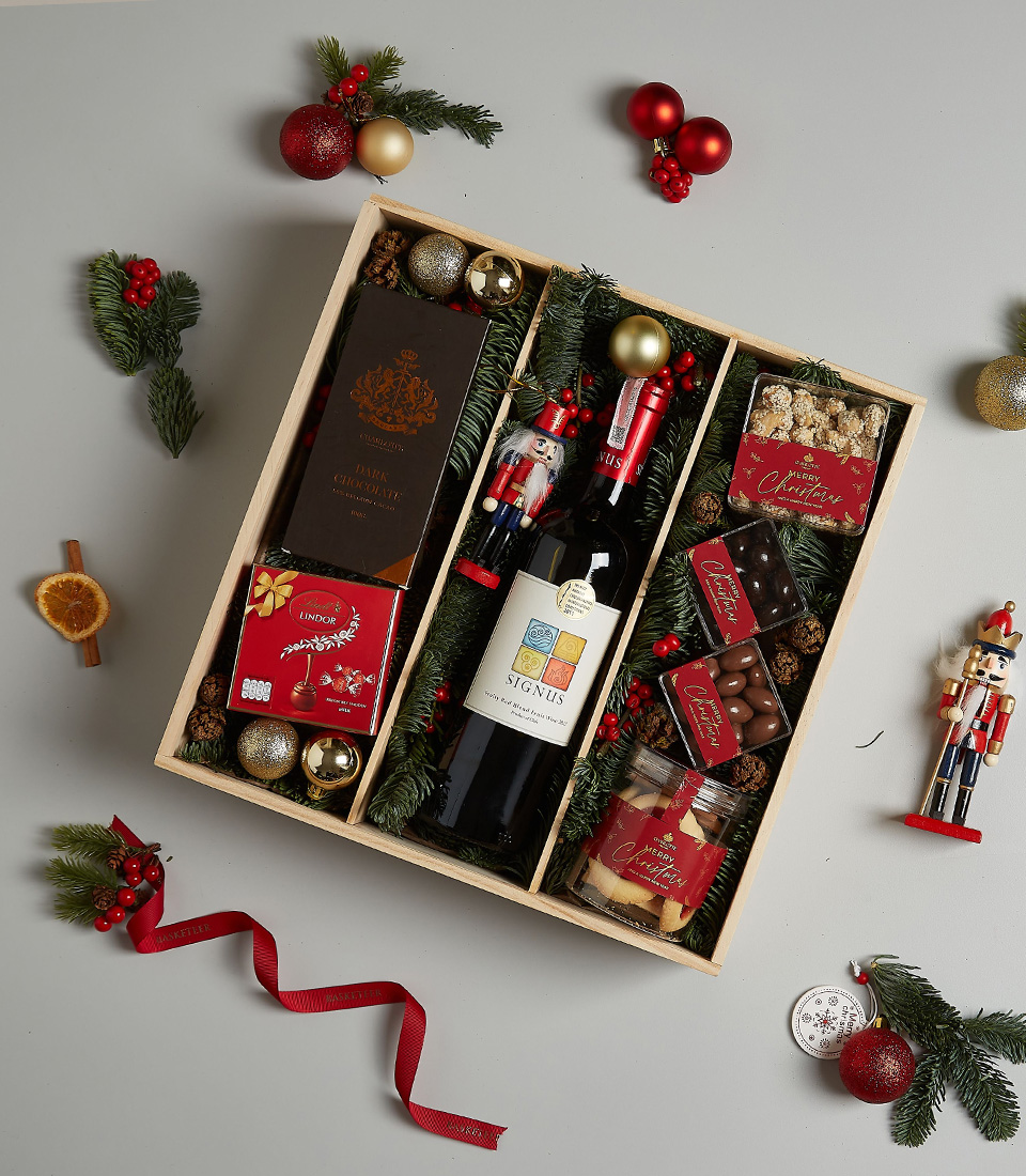 Holiday gift box with Signus wine, dark chocolate, Lindt pralines, festive cookies, and holiday decorations, elegantly packaged for Christmas celebrations.