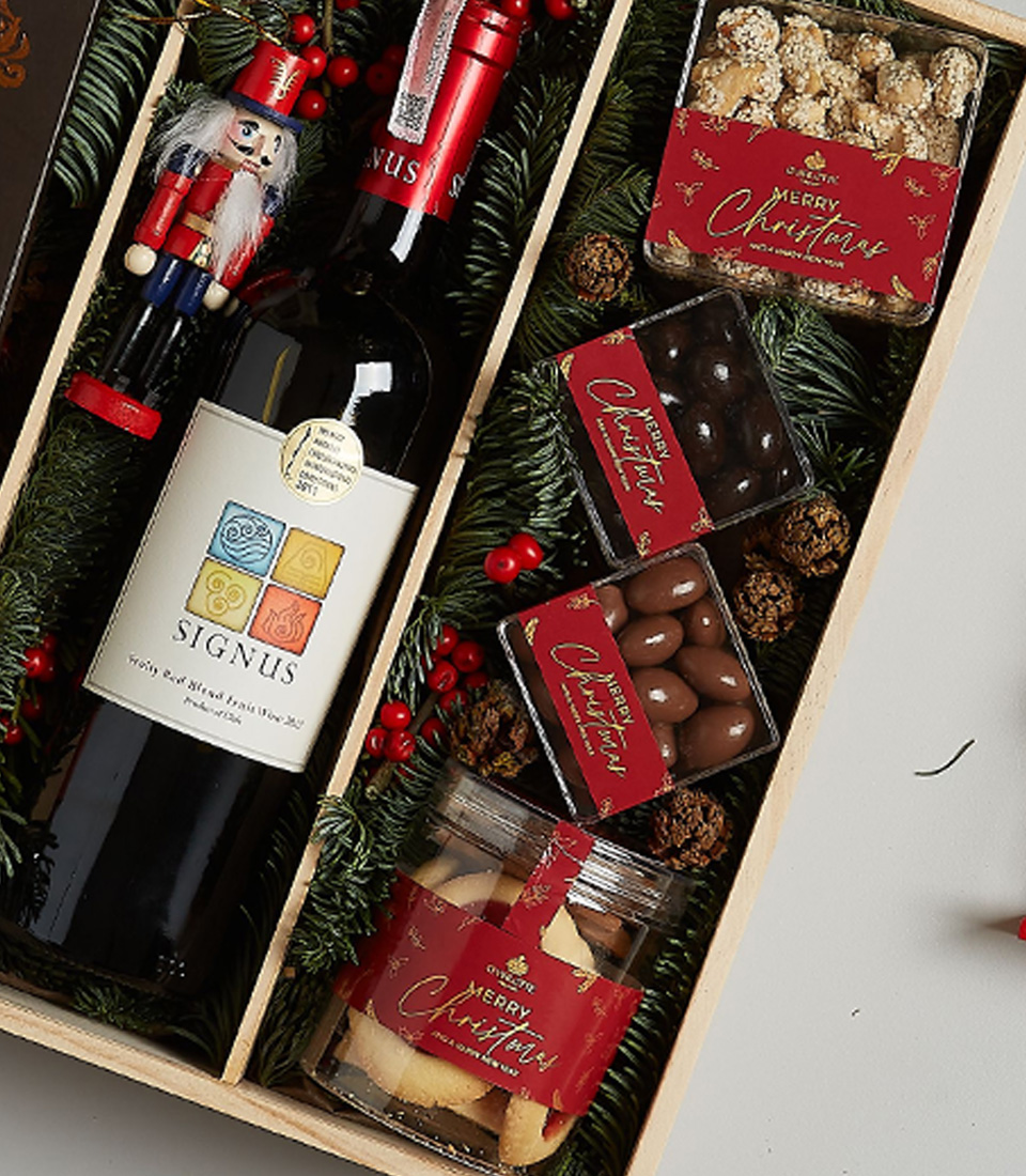 Holiday gift box with Signus wine, dark chocolate, Lindt pralines, festive cookies, and holiday decorations, elegantly packaged for Christmas celebrations.