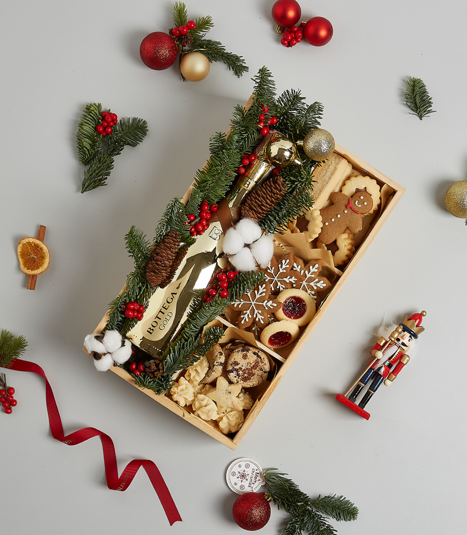 Holiday gift box with Bottega Gold sparkling wine, festive cookies, gingerbread, snowflake treats, and holiday greenery decorations.