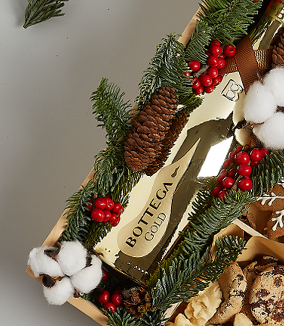 Holiday gift box with Bottega Gold sparkling wine, festive cookies, gingerbread, snowflake treats, and holiday greenery decorations.