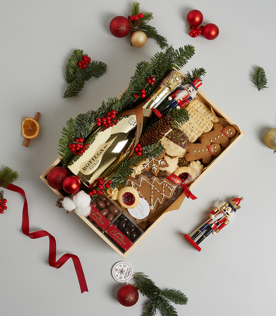Gift box featuring Bottega Gold Prosecco, festive cookies, gingerbread, and holiday-themed decorations, including greenery and nutcracker ornaments.