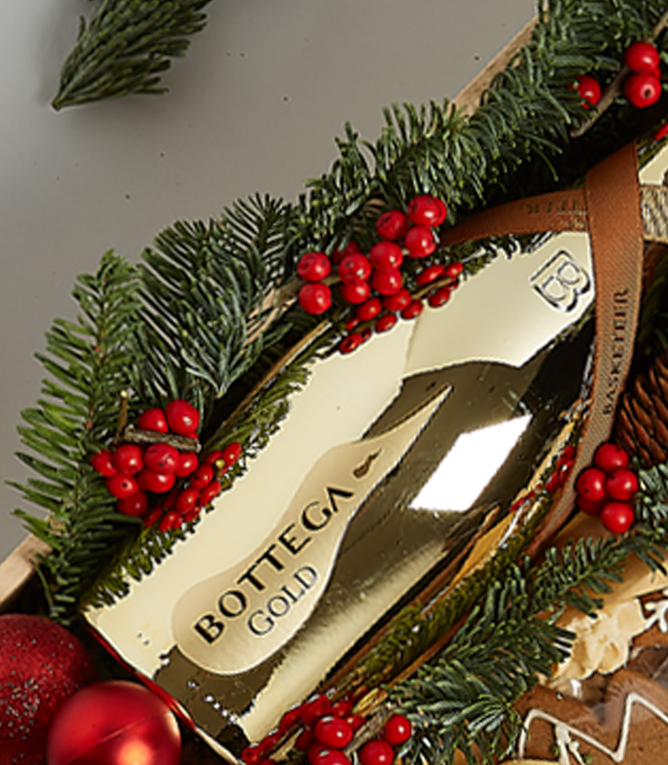 Gift box featuring Bottega Gold Prosecco, festive cookies, gingerbread, and holiday-themed decorations, including greenery and nutcracker ornaments.