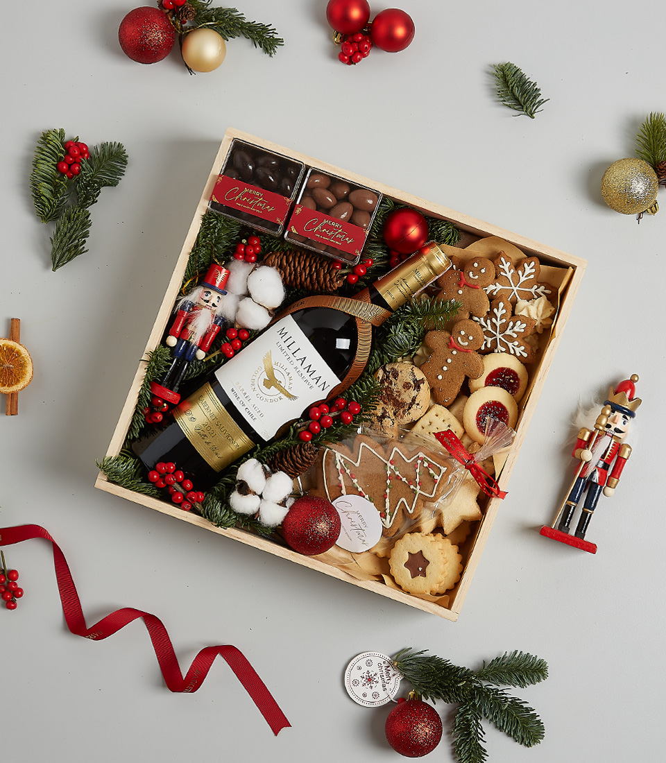 Christmas gift box with William Fevre Chardonnay, gingerbread cookies, chocolates, shortbread biscuits, festive greenery, and a nutcracker ornament.