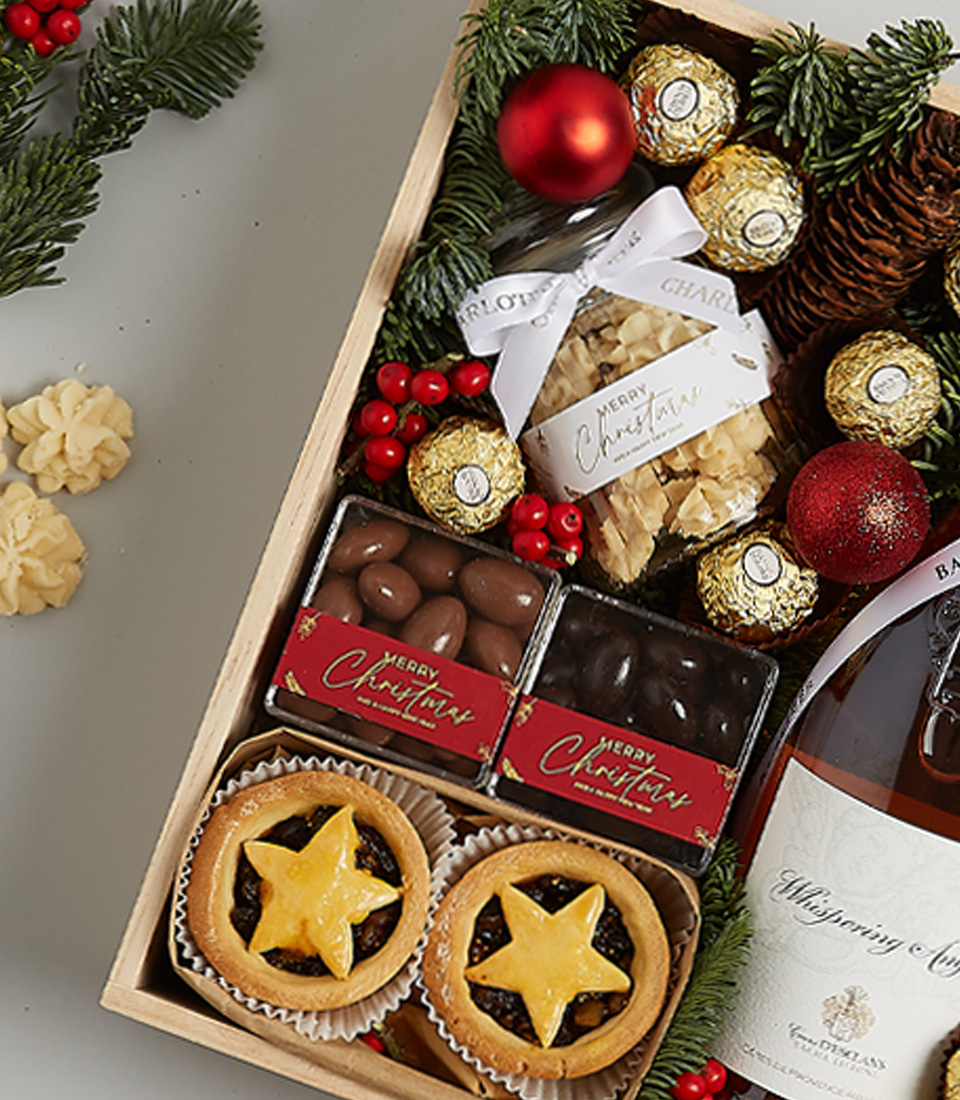 Christmas hamper with Château Montaud Rosé, mince pies, Ferrero Rocher chocolates, gingerbread cookies, festive greenery, and a nutcracker ornament.